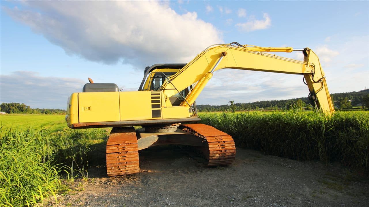 Excavator working in a green agricultural field